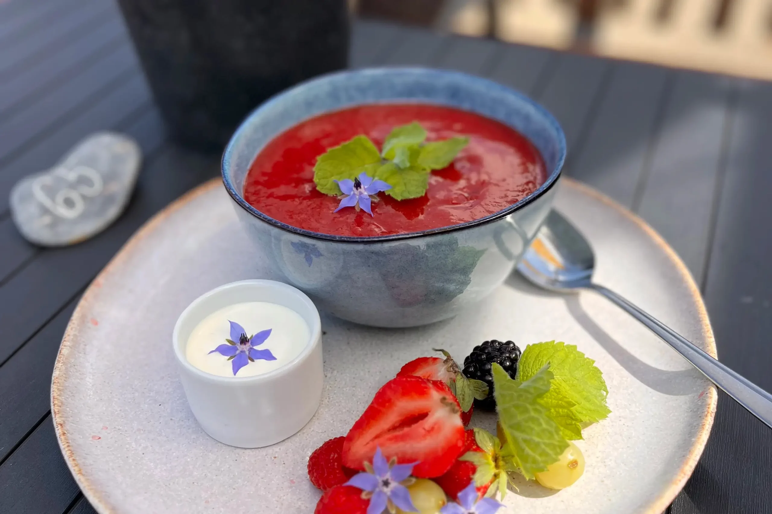 Sommerdessert af jordbærgrød med fløde, friske bær og spiselige blomster i Restaurant Slettestrand